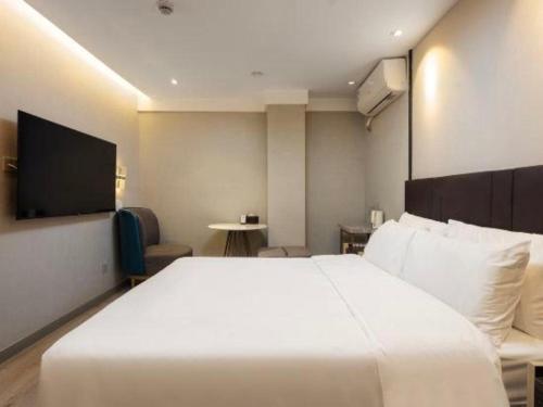 a hotel room with a white bed and a tv at Magnotel Shanghai Maglev Station in Shanghai