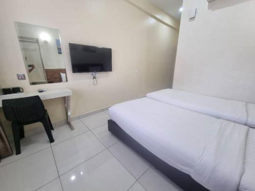 a hotel room with a bed and a desk and a television at Avatel Jelutong in George Town