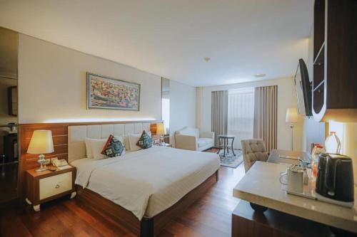 a hotel room with a bed and a living room at Grand Qin Hotel Syariah in Banjarbaru