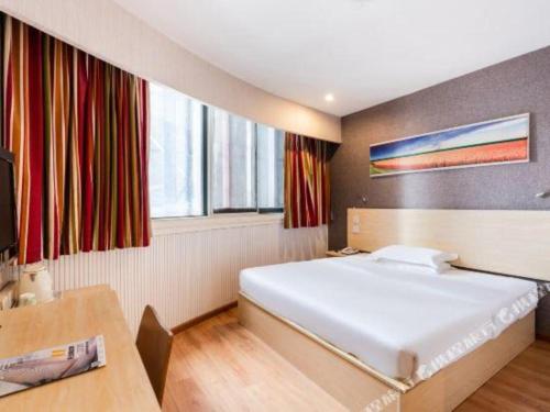 a bedroom with a large white bed and a desk at 7 Days Inn Chengdu Huayang Metro Station Binfen Plaza in Chengdu