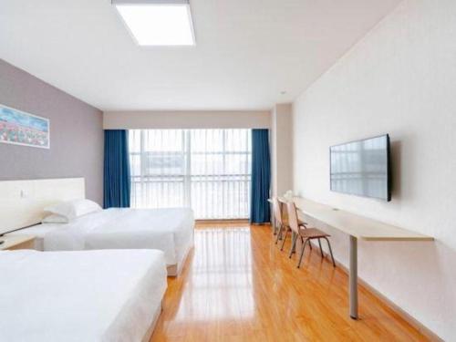 a hotel room with two beds and a desk and a table at 7 Days Inn Chengdu Huayang Metro Station Binfen Plaza in Chengdu