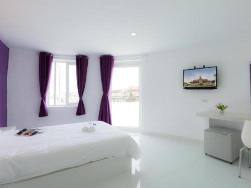 a white bedroom with purple curtains and a bed at Hotel Zing Phnom Penh in Phnom Penh