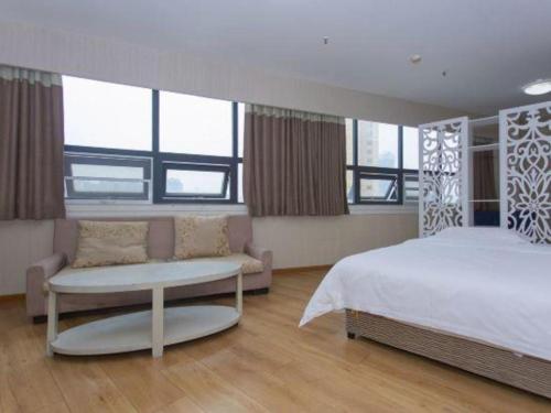 a bedroom with a bed and a couch and windows at 7 Days Inn Chengdu Huayang Metro Station Binfen Plaza in Chengdu