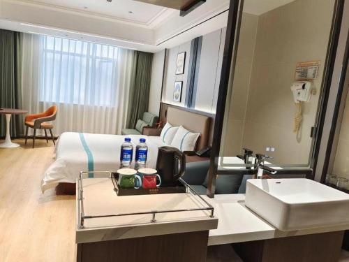 a hotel room with a bed and a sink and a mirror at GreenTree Inn Wuhu Fanchang County Anding Road Hotel in Wuhu