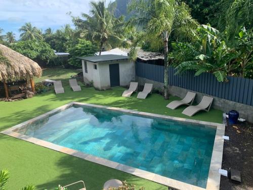 a swimming pool with lounge chairs in a yard at Tiki Ora Lodge - HURA in Bora Bora