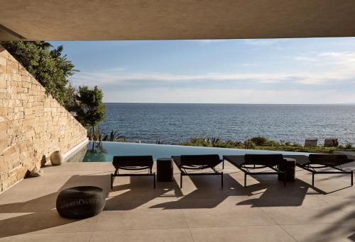 a patio with chairs and a view of the ocean at Opsis villas, A waterfront & architectural retreat in Akrotiri