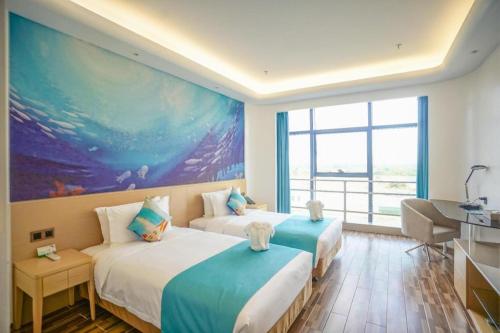 two beds in a room with a large painting on the wall at Beluga Sanya Discovery Ocean World in Shangsimacun