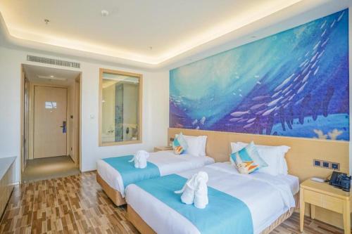 a hotel room with two beds with towels on them at Beluga Sanya Discovery Ocean World in Shangsimacun