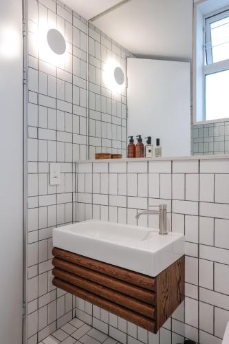a white tiled bathroom with a sink and a mirror at Seaside 8 l Aparthotel 50m from the Promenade in Cape Town