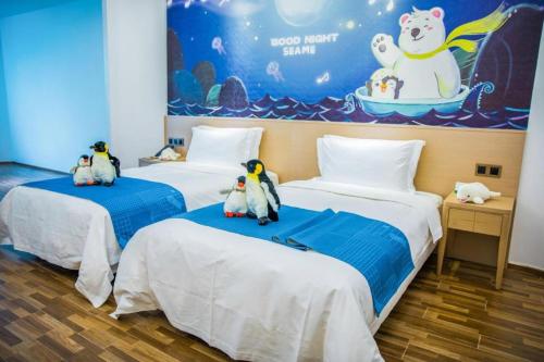 two beds with penguins sitting on them in a room at Beluga Sanya Discovery Ocean World in Shangsimacun