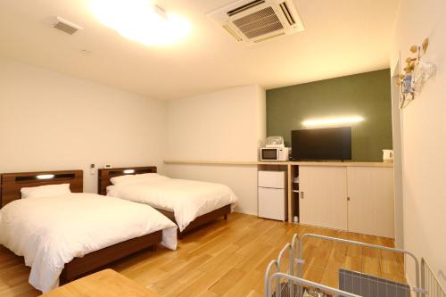 a hotel room with two beds and a tv at ホテル森のしずく in Shimoda