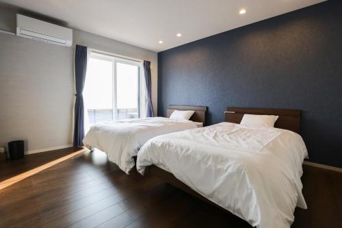 two beds in a bedroom with a large window at マーレブル仙崎 in Nagato