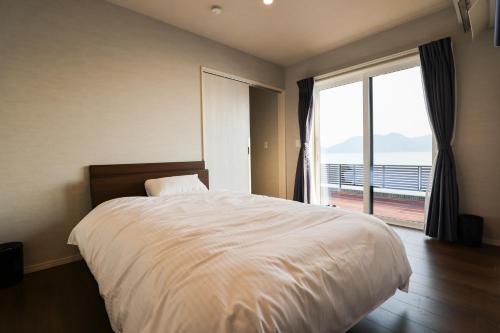 a bedroom with a large bed and a large window at マーレブル仙崎 in Nagato