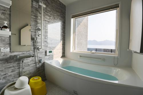 a bathroom with a bath tub and a window at マーレブル仙崎 in Nagato