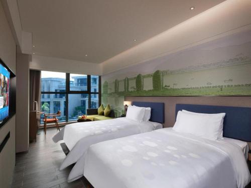 a hotel room with two beds and a television at Hampton by Hilton Sanya Weiming Lake Park in Sanya