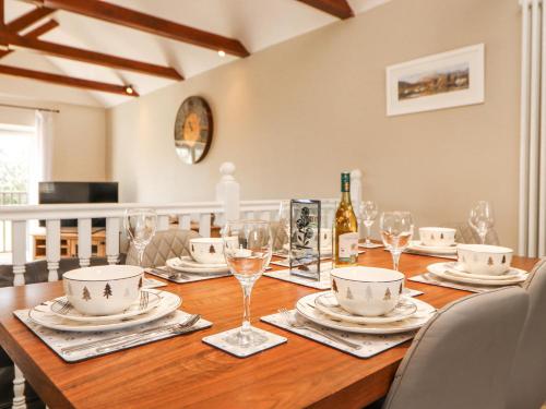 a wooden table with plates and wine glasses on it at Squirrel Cottage in Penrith