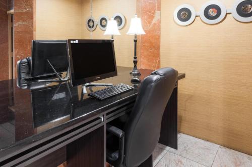 a desk with a computer monitor and a keyboard at Ramada by Wyndham Newburgh/West Point in Newburgh