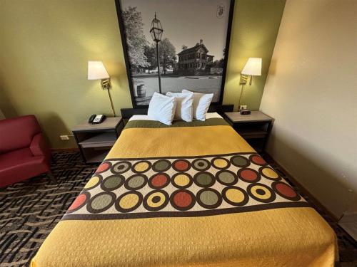 a hotel room with a bed and a red couch at Super 8 by Wyndham McLean/Bloomington SW in McLean
