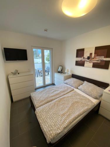 a bedroom with a large bed and a television at Apartments Katharina in Batalaži