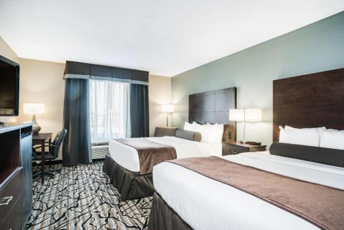 a hotel room with two beds and a flat screen tv at Days Inn & Suites by Wyndham Wausau in Wausau