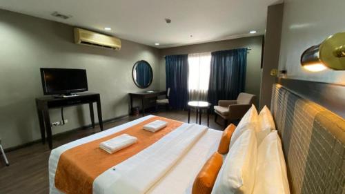 a hotel room with a large bed and a television at Baguio Burnham Suites Hotel in Baguio