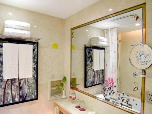 a bathroom with a sink and a large mirror at Changsha Huatian Hotel in Changsha