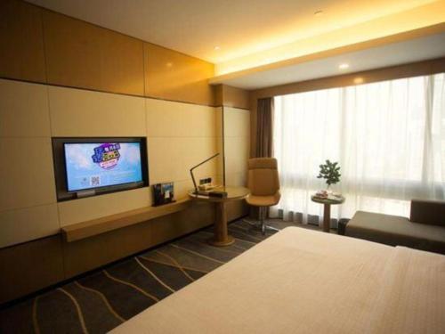 a hotel room with a television and a couch and a chair at Changsha Huatian Hotel in Changsha