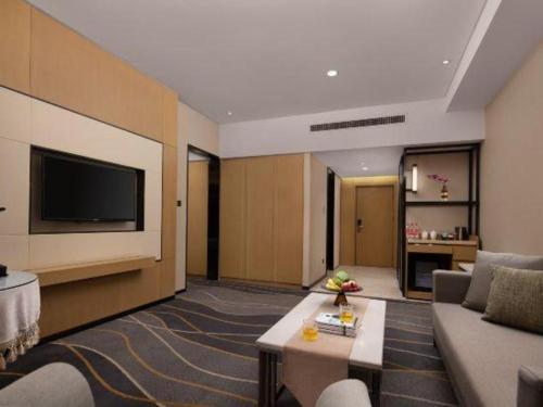 a living room with a couch and a tv at Changsha Huatian Hotel in Changsha