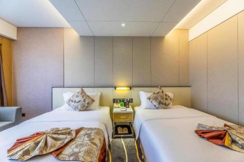 a hotel room with two beds and a desk at Changsha Huatian Hotel in Changsha