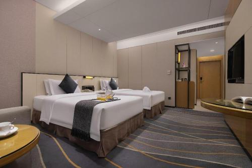 a hotel room with two beds and a television at Changsha Huatian Hotel in Changsha