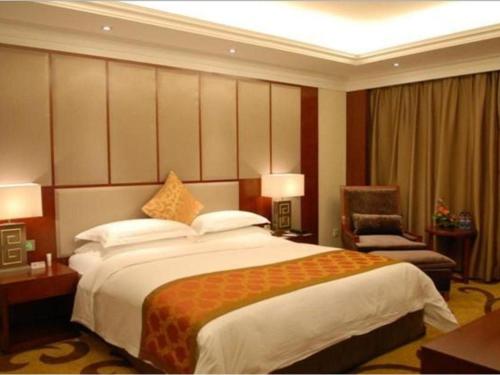 a hotel room with a large bed and a chair at Changsha Huatian Hotel in Changsha