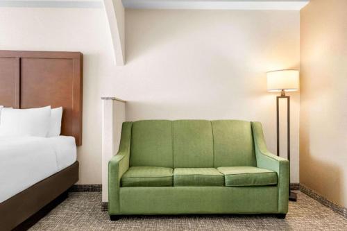 a green couch in a hotel room with a bed at Comfort Inn & Suites in Riverton