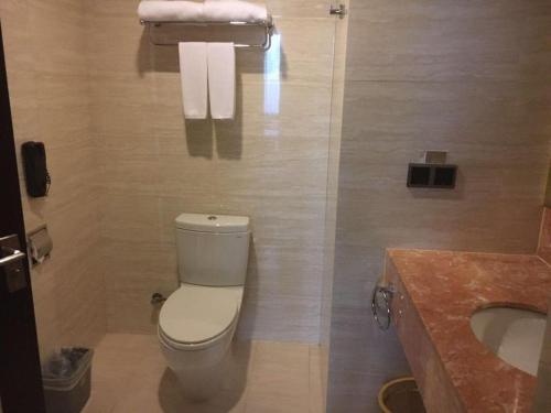 a bathroom with a toilet and a sink and towels at New Century Manju Hotel Shanghai New International Expo Center in Shanghai