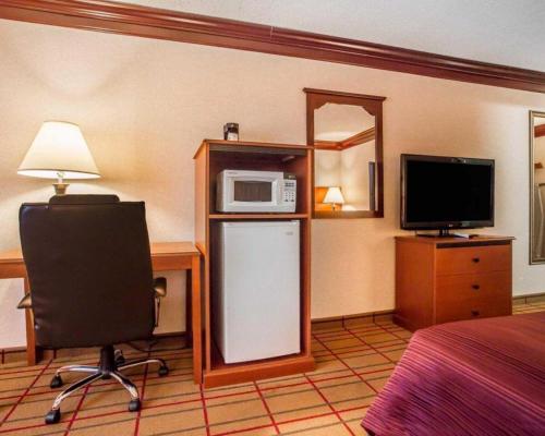 a hotel room with a bed and a microwave and a chair at Quality Inn & Conference Center in Brattleboro
