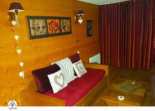 - un salon avec un canapé rouge et des oreillers dans l'établissement Les 3 Vallées Apartment, à Brides-les-Bains