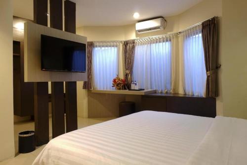 a bedroom with a bed with a tv and windows at Alexander Hotel Tegal in Tegal