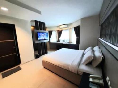 a bedroom with a bed and a flat screen tv at Alexander Hotel Tegal in Tegal