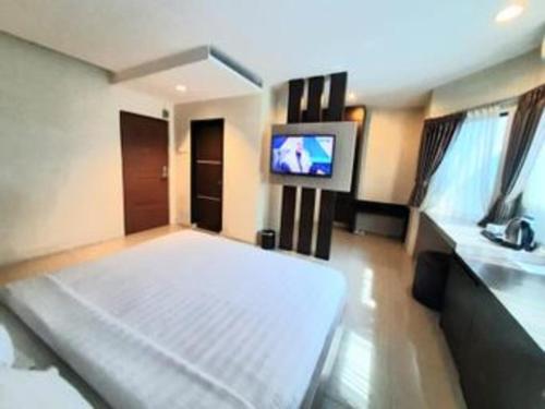 a bedroom with a large bed and a flat screen tv at Alexander Hotel Tegal in Tegal
