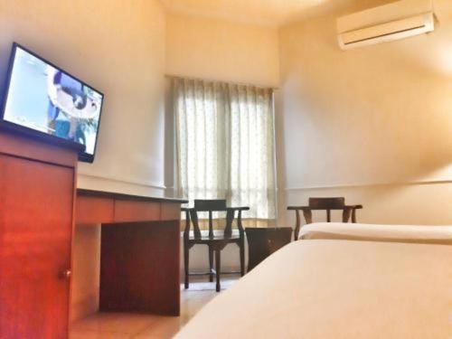 a hotel room with a bed and a flat screen tv at Alexander Hotel Tegal in Tegal
