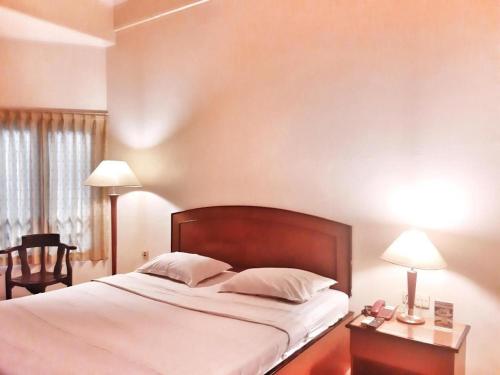 a bedroom with a bed and a table with two lamps at Alexander Hotel Tegal in Tegal