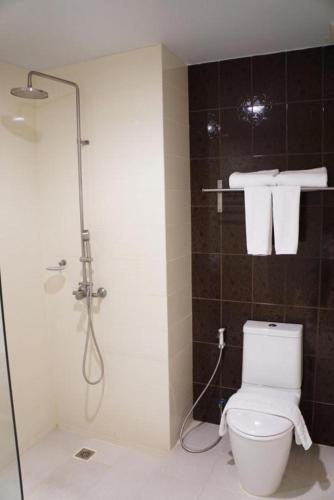 a bathroom with a toilet and a shower with towels at The One Residence Hotel in Bangkok