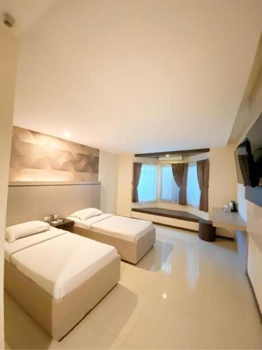 a bedroom with two beds and a flat screen tv at Alexander Hotel Tegal in Tegal