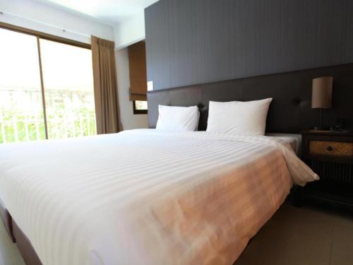 a bedroom with a large white bed with a window at The One Residence Hotel in Bangkok
