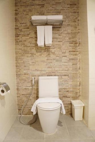 a bathroom with a toilet and towels on a brick wall at The One Residence Hotel in Bangkok