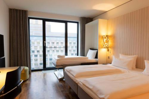 a hotel room with two beds and a large window at Scandic Berlin Potsdamer Platz in Berlin