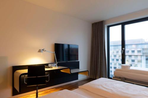 a hotel room with a desk and a bed and a window at Scandic Berlin Potsdamer Platz in Berlin