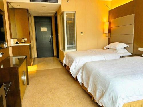 a hotel room with two beds and a bathroom at Jiaxin Conifer Hotel Shunde in Shunde