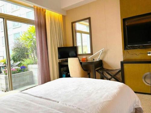 a bedroom with a bed and a desk with a computer at Jiaxin Conifer Hotel Shunde in Shunde
