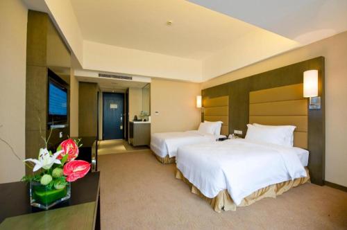 a hotel room with two beds and a television at Jiaxin Conifer Hotel Shunde in Shunde