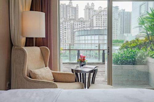 a hotel room with a bed and a chair and a window at Jiaxin Conifer Hotel Shunde in Shunde